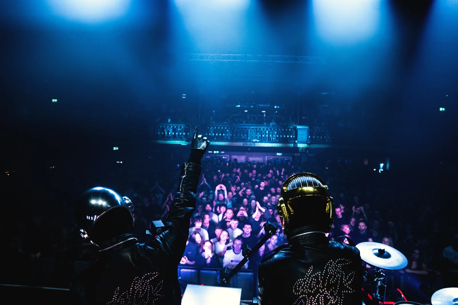 The crowd seen from the stage at a Daft Funk Live show, a fist raised under blue light